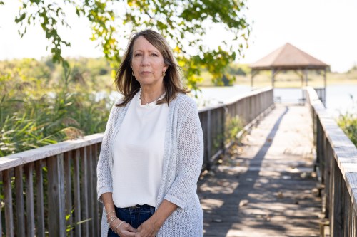 A photo of a woman standing outside on a dock by a gazebo.