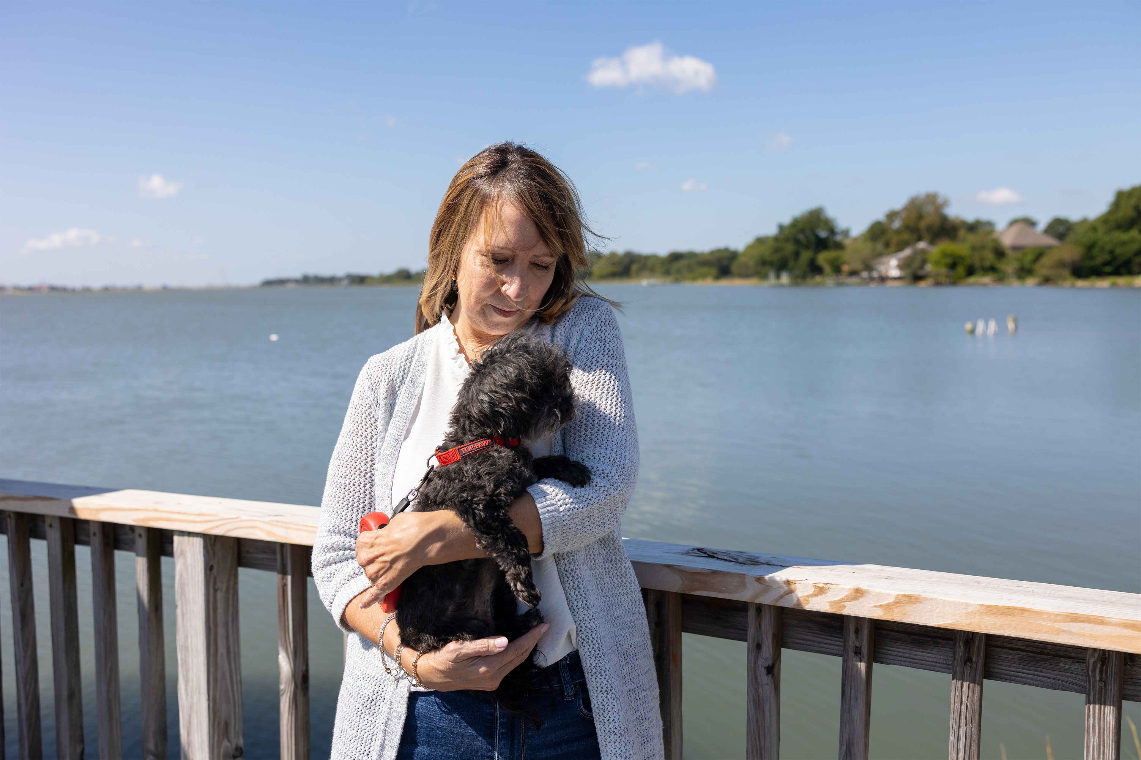 A photo of a woman holding her dog outside.