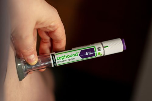 A photo of someone using a Zepbound injector pen on their stomach.