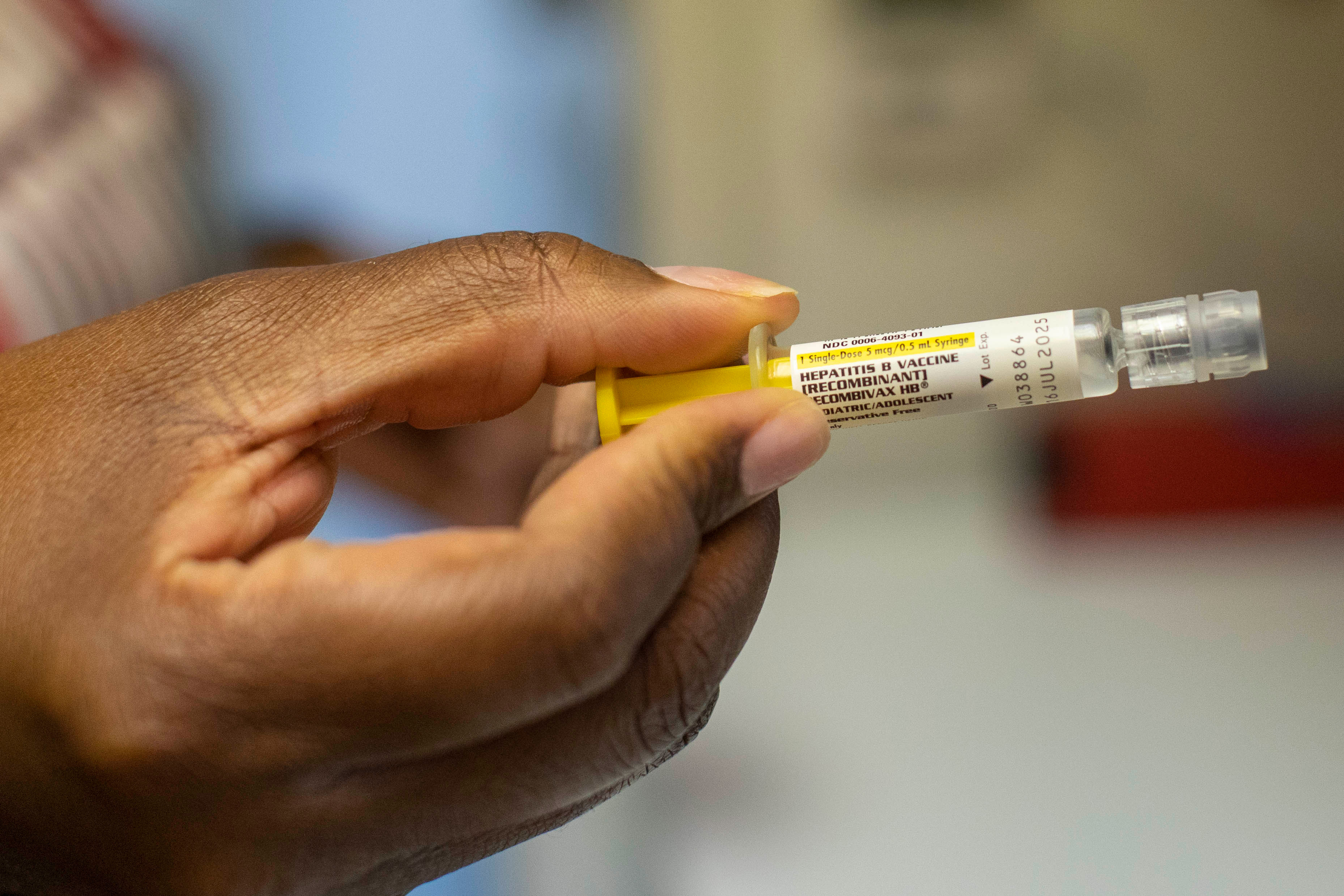 A photo of a hand holding a syringe of the hepatitis B vaccine.