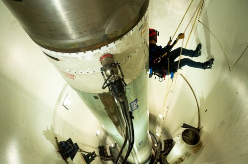 A photo of a firefighter repelling on cords inside of a missile silo.