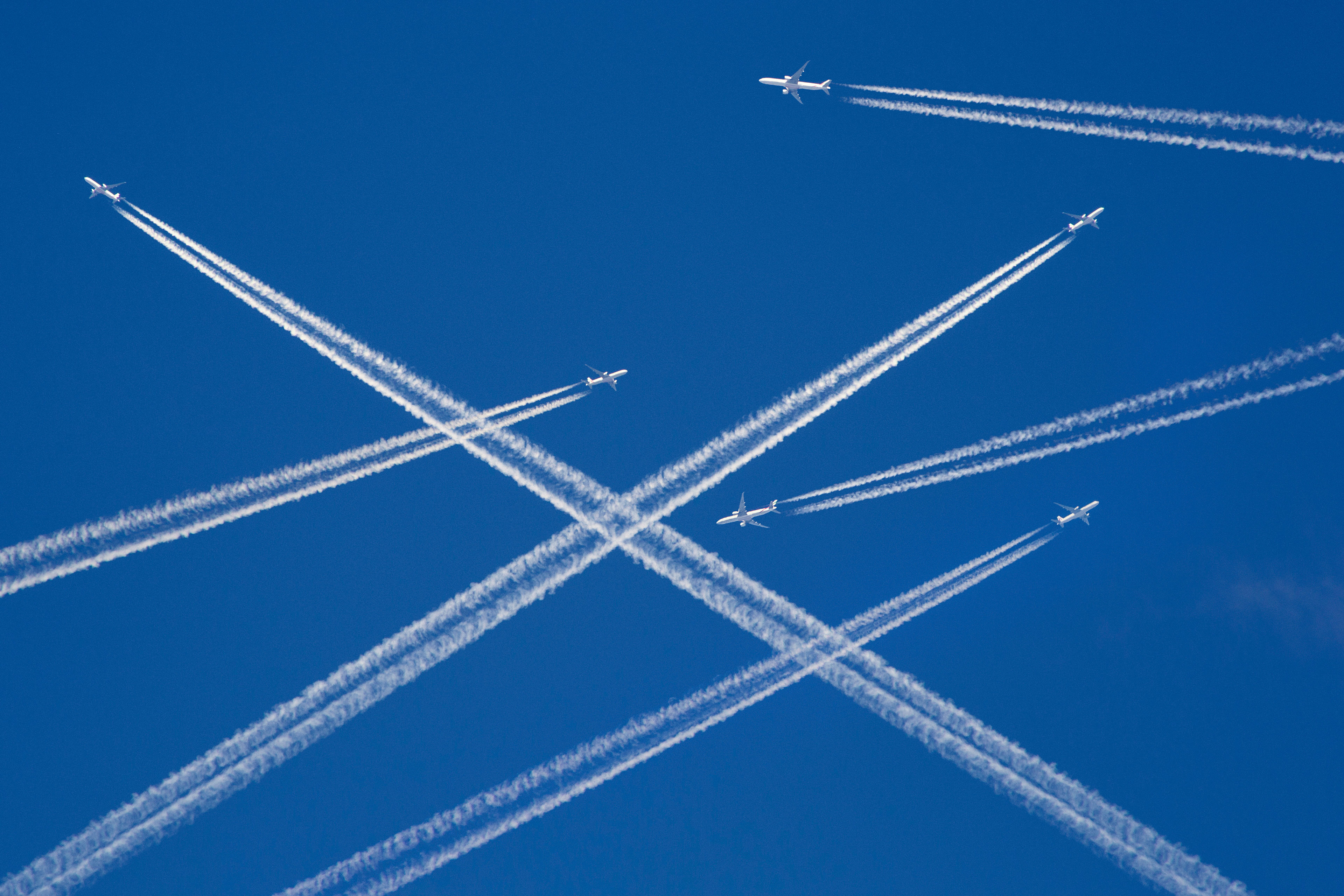 A photo illustration of a sky filled with airplanes releasing contrails behind them.