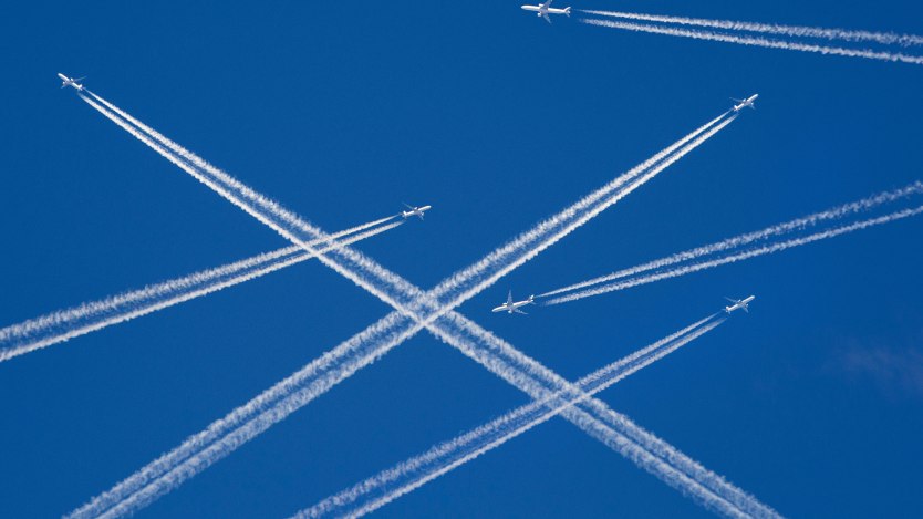 A photo illustration of a sky filled with airplanes releasing contrails behind them.