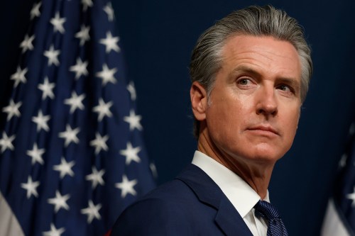 A photo of Gov. Gavin Newsom at a news conference with an American flag behind him.