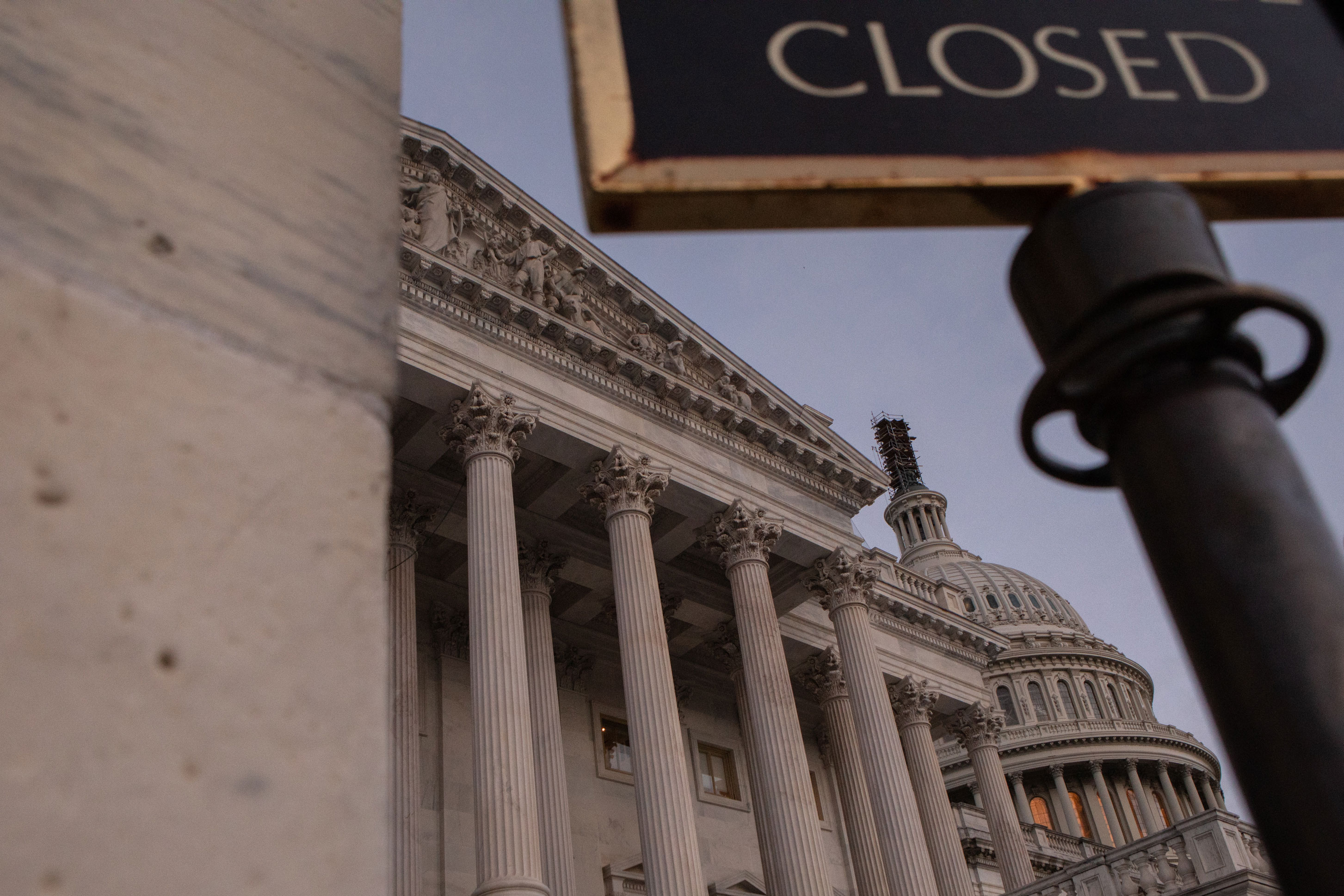 A photo of the U.S. Capitol. In the foreground is part of a sign that reads, "closed."