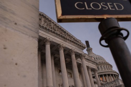 A photo of the U.S. Capitol. In the foreground is part of a sign that reads, "closed."