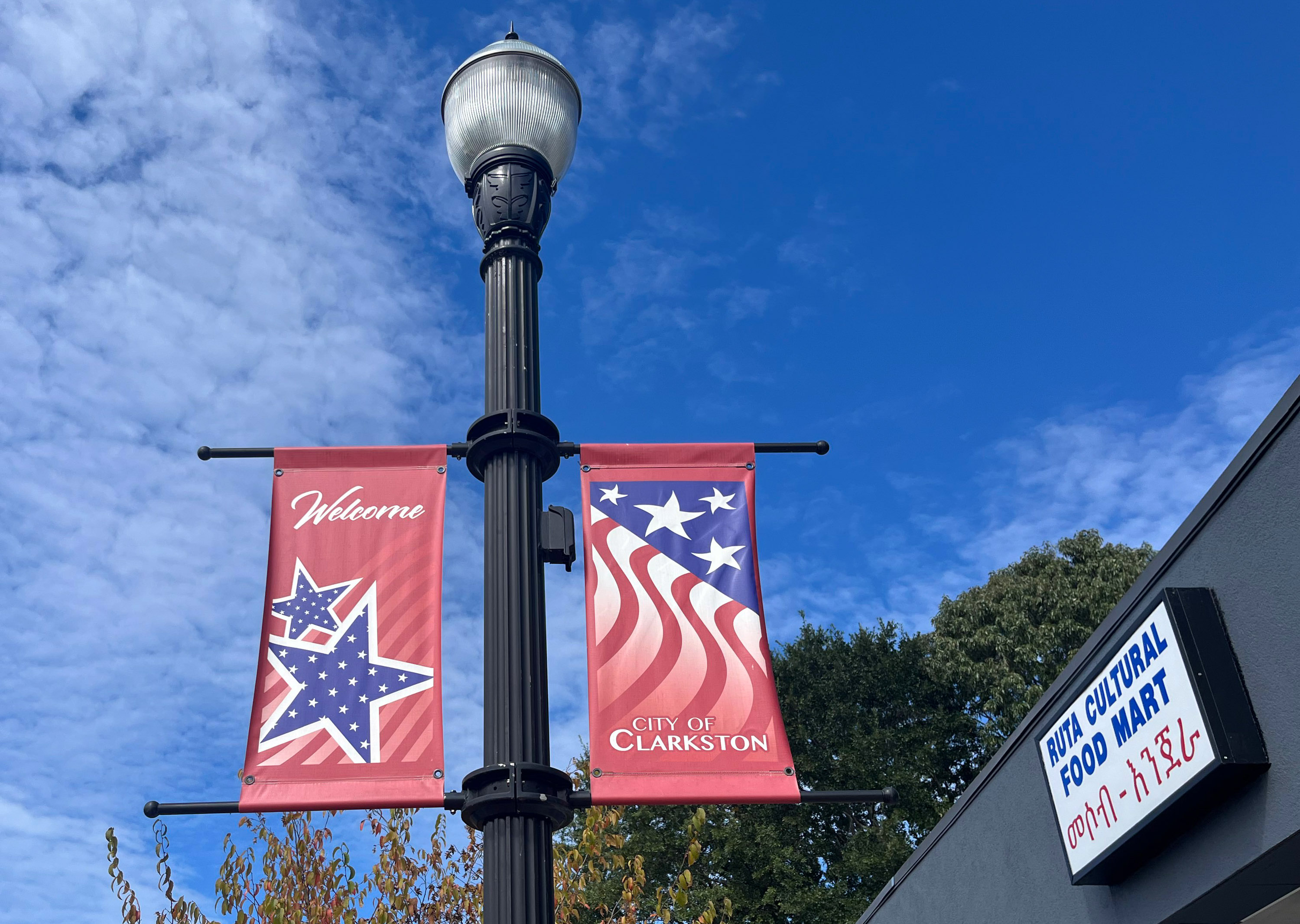 A photo of a lamppost with two banners. The left banner reads, "Welcome." The right reads, "City of Clarkston."