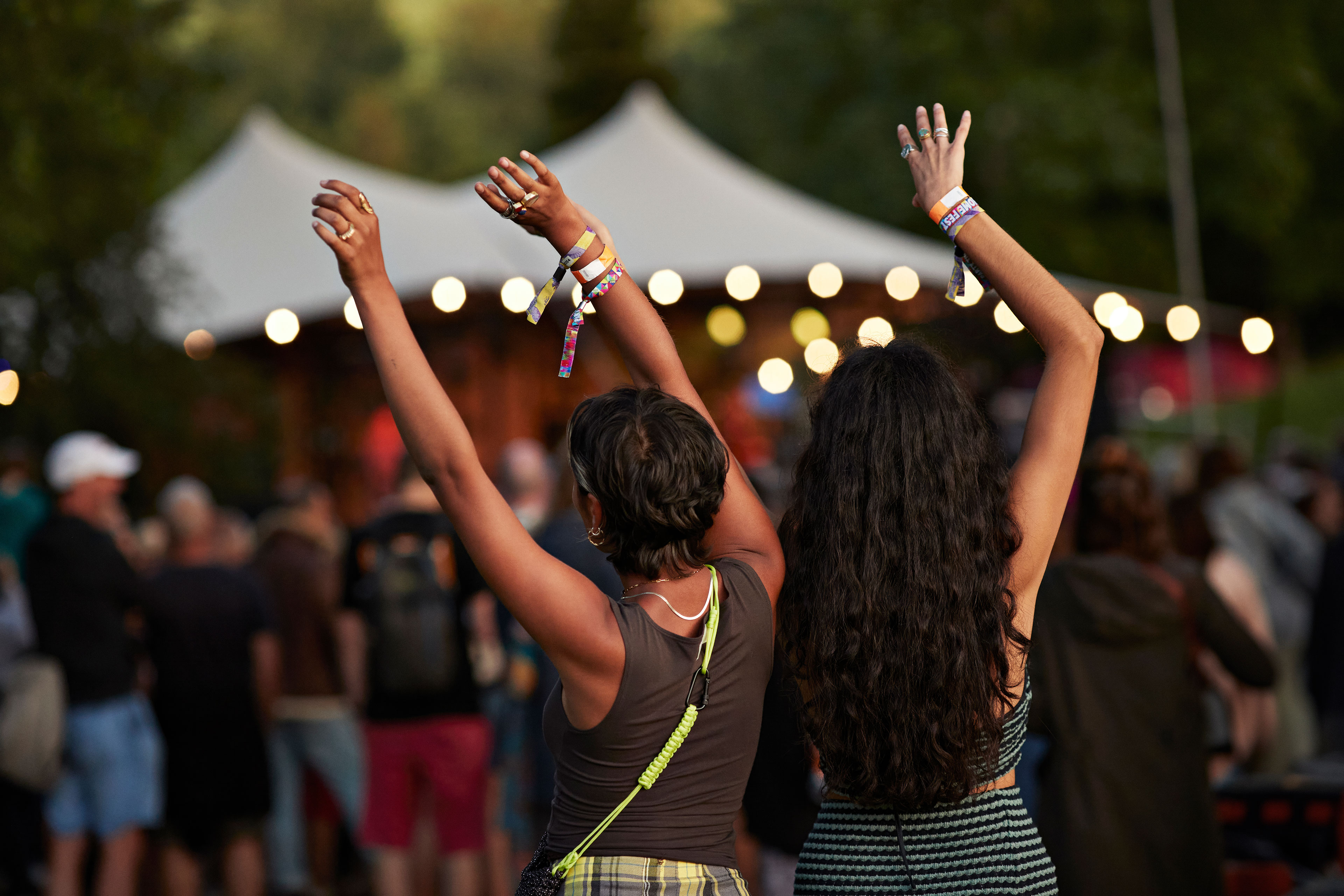 Two people dancing with their arms in the air at an outdoor concert.