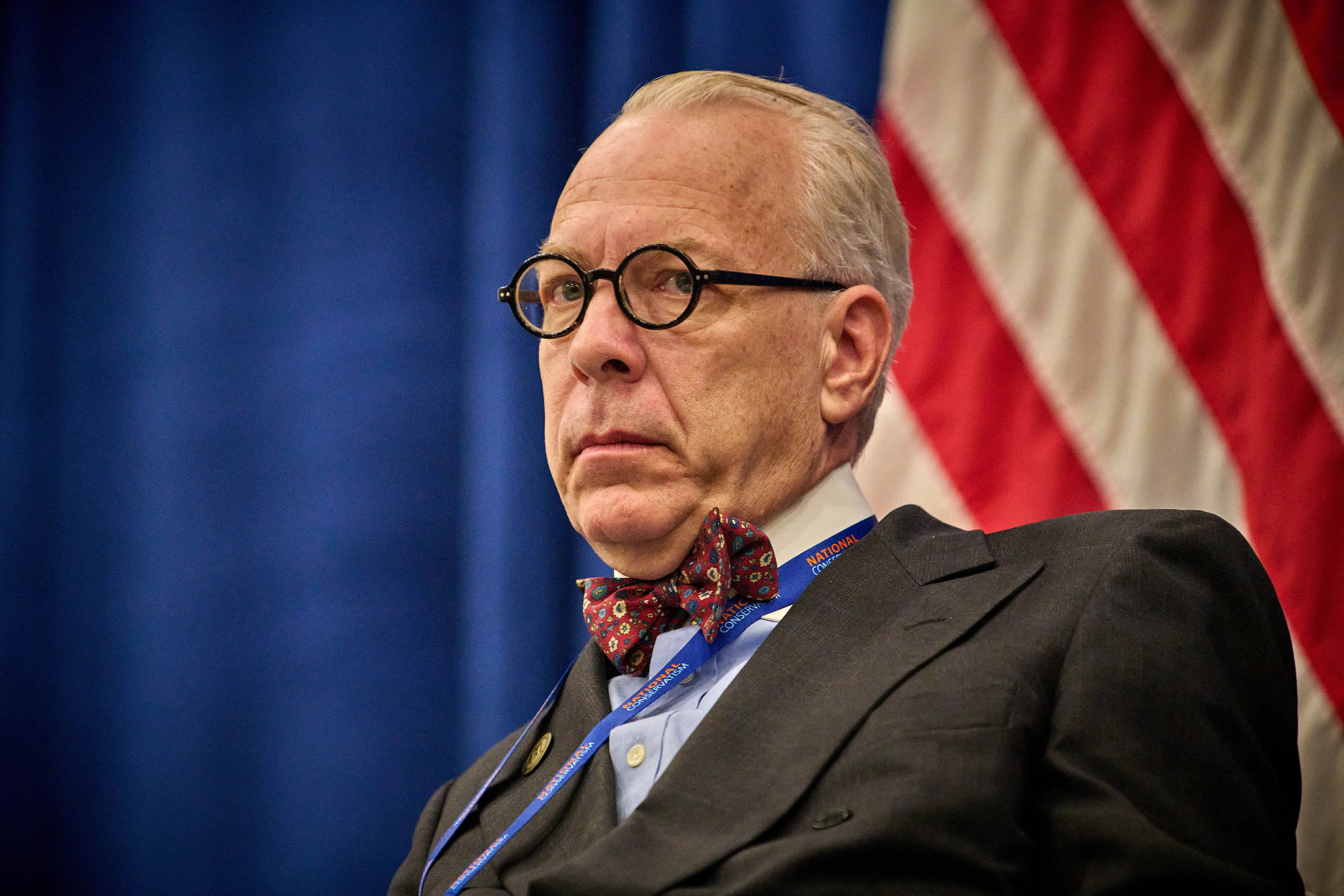 A close shot of a senior man with black round glasses.