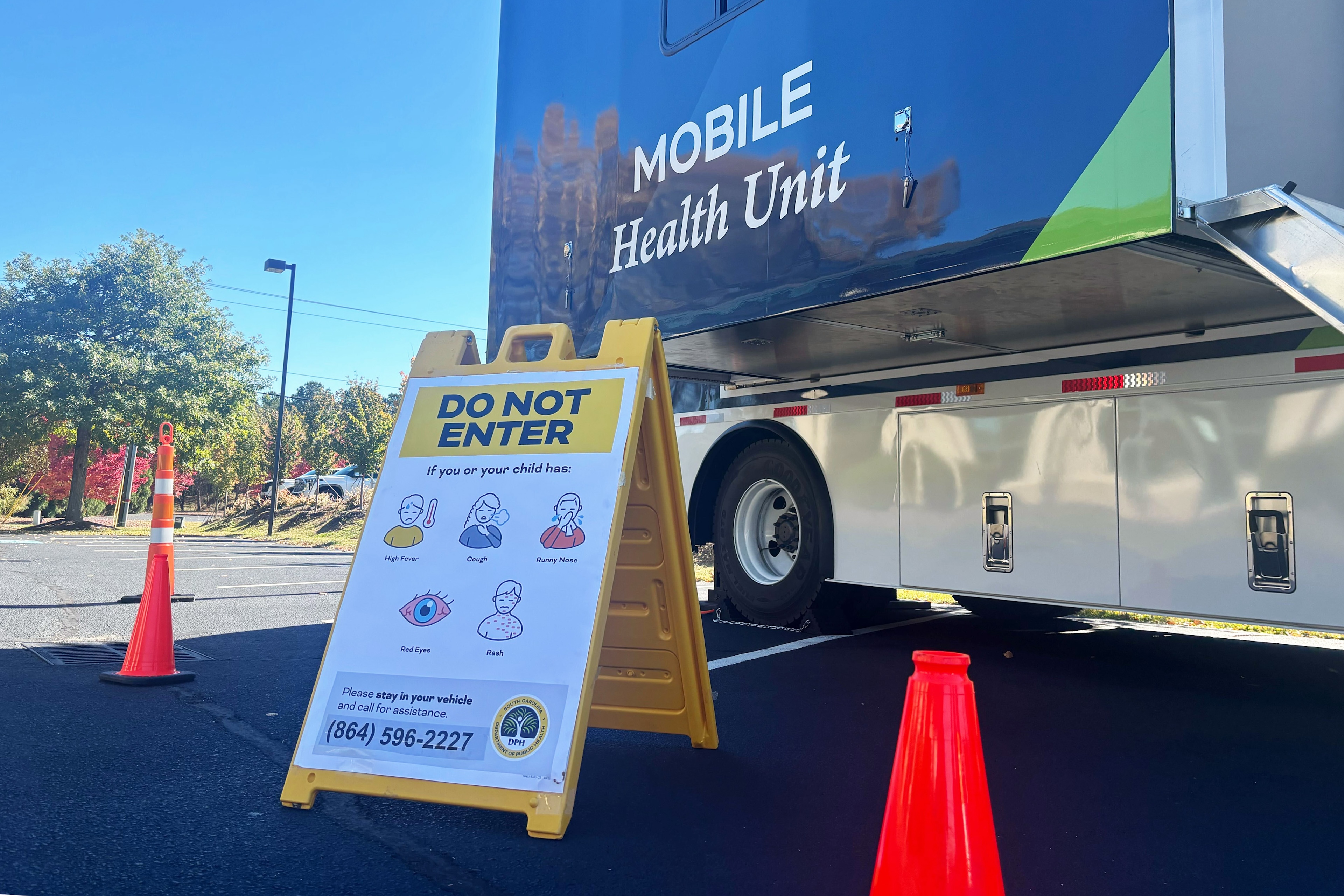 A mobile health van with a yellow a-frame side out front reading "do not enter"
