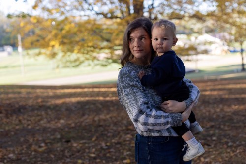 A photo of a woman holding her toddler outside.