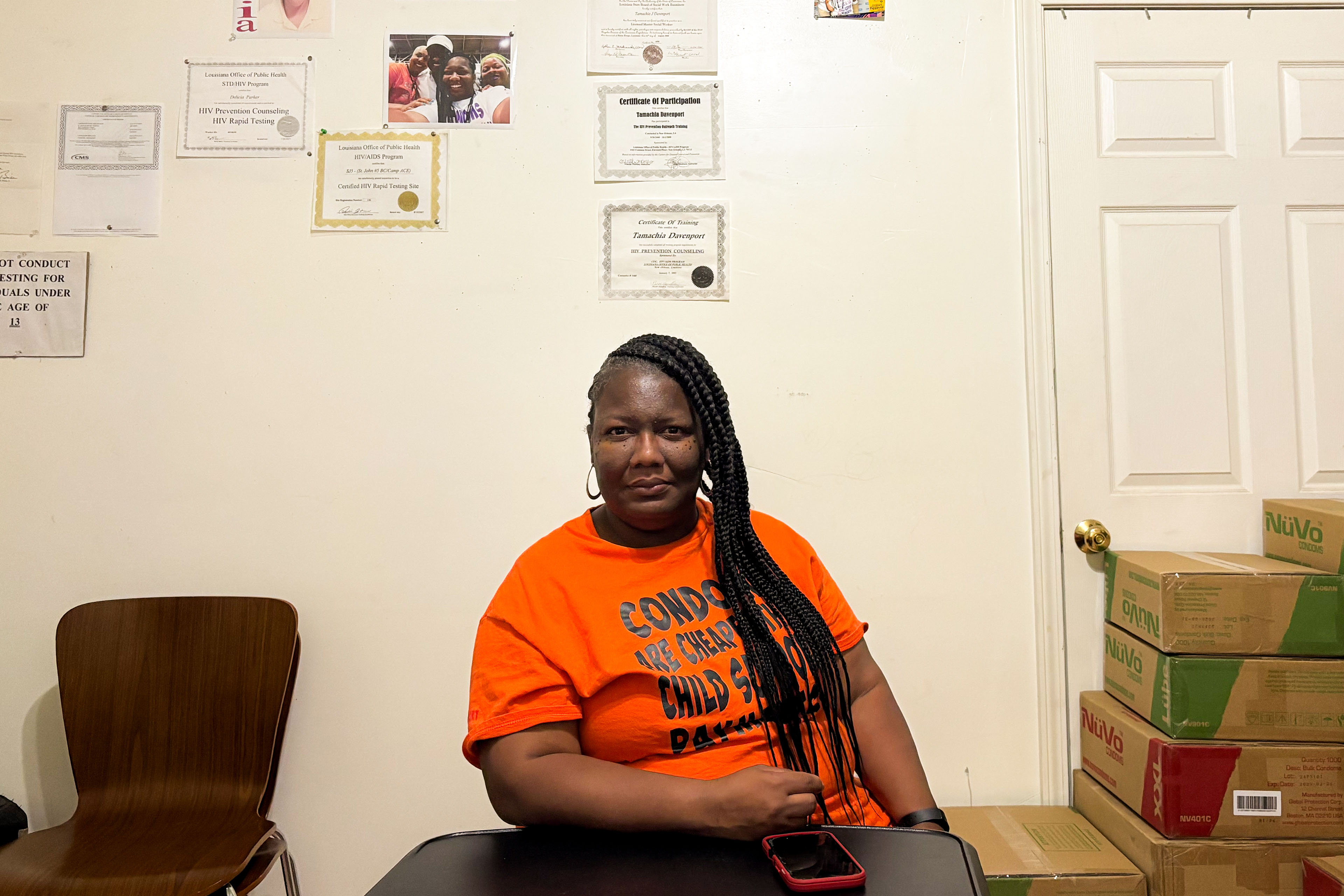 A portrait of a woman sitting in her office with an array of credentials on the wall behind her.