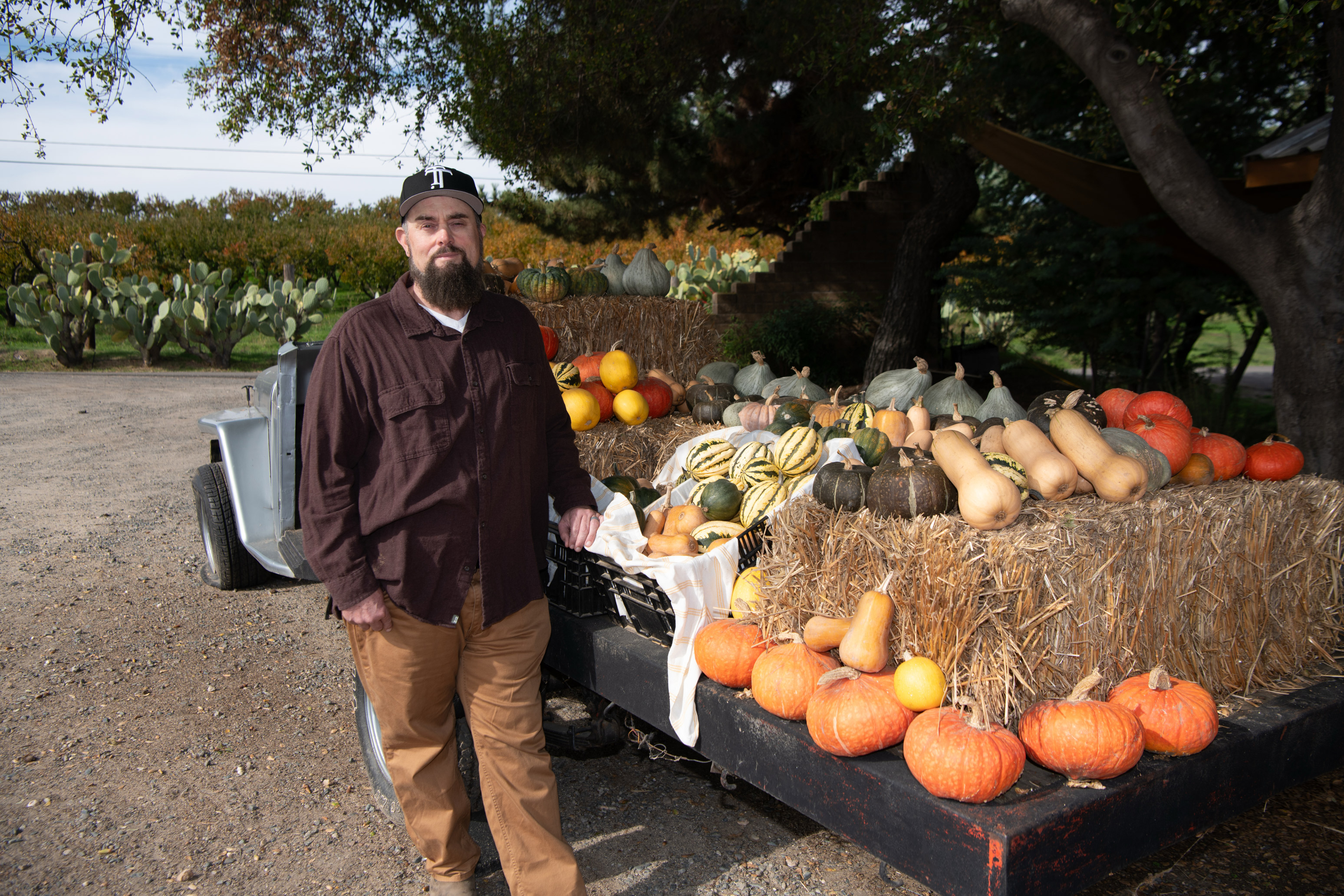 A photo of Justin Miller at his farmers market stand. Pumpkins and squash are seen on the table.