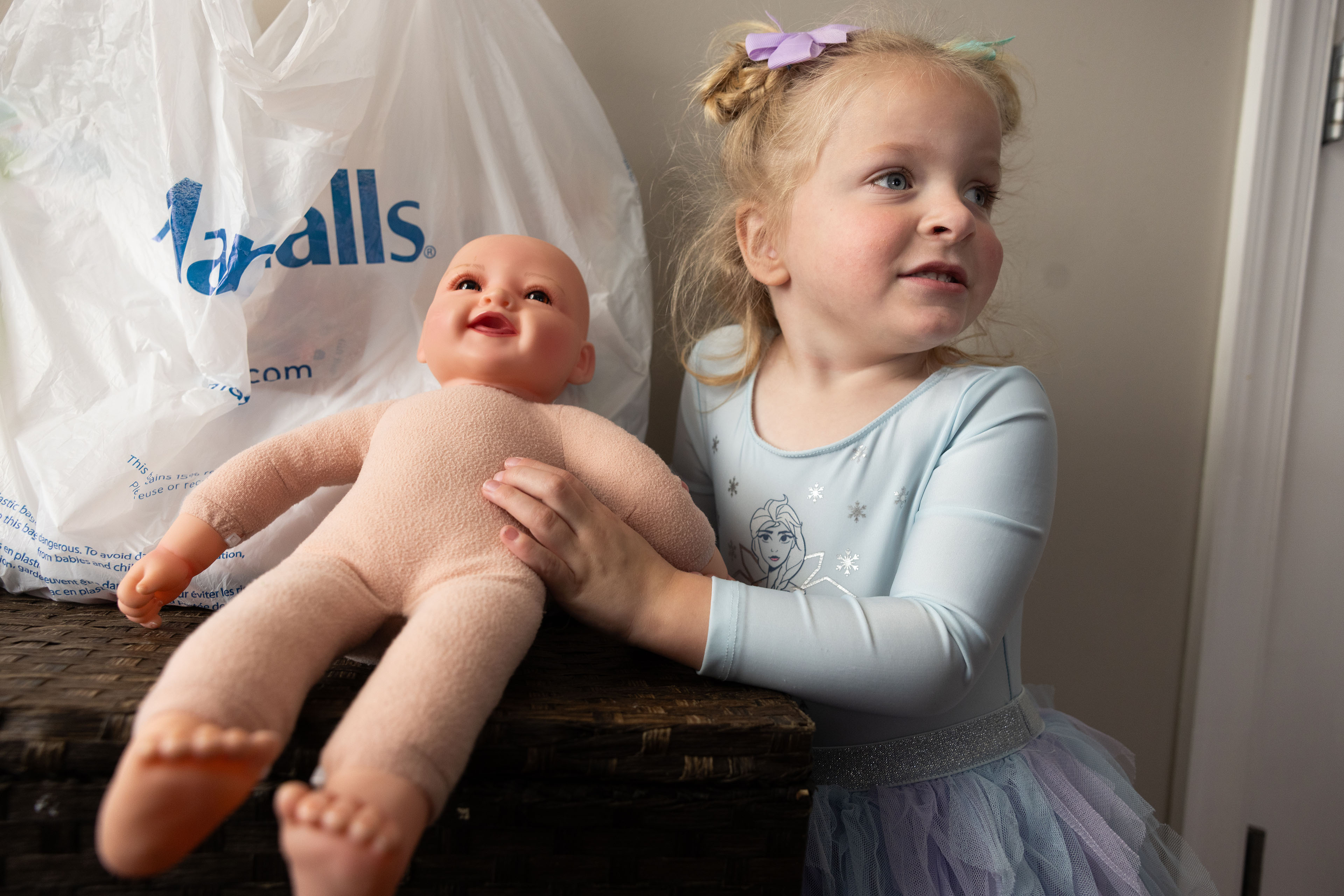 A 3-year-old girl holds a baby doll.