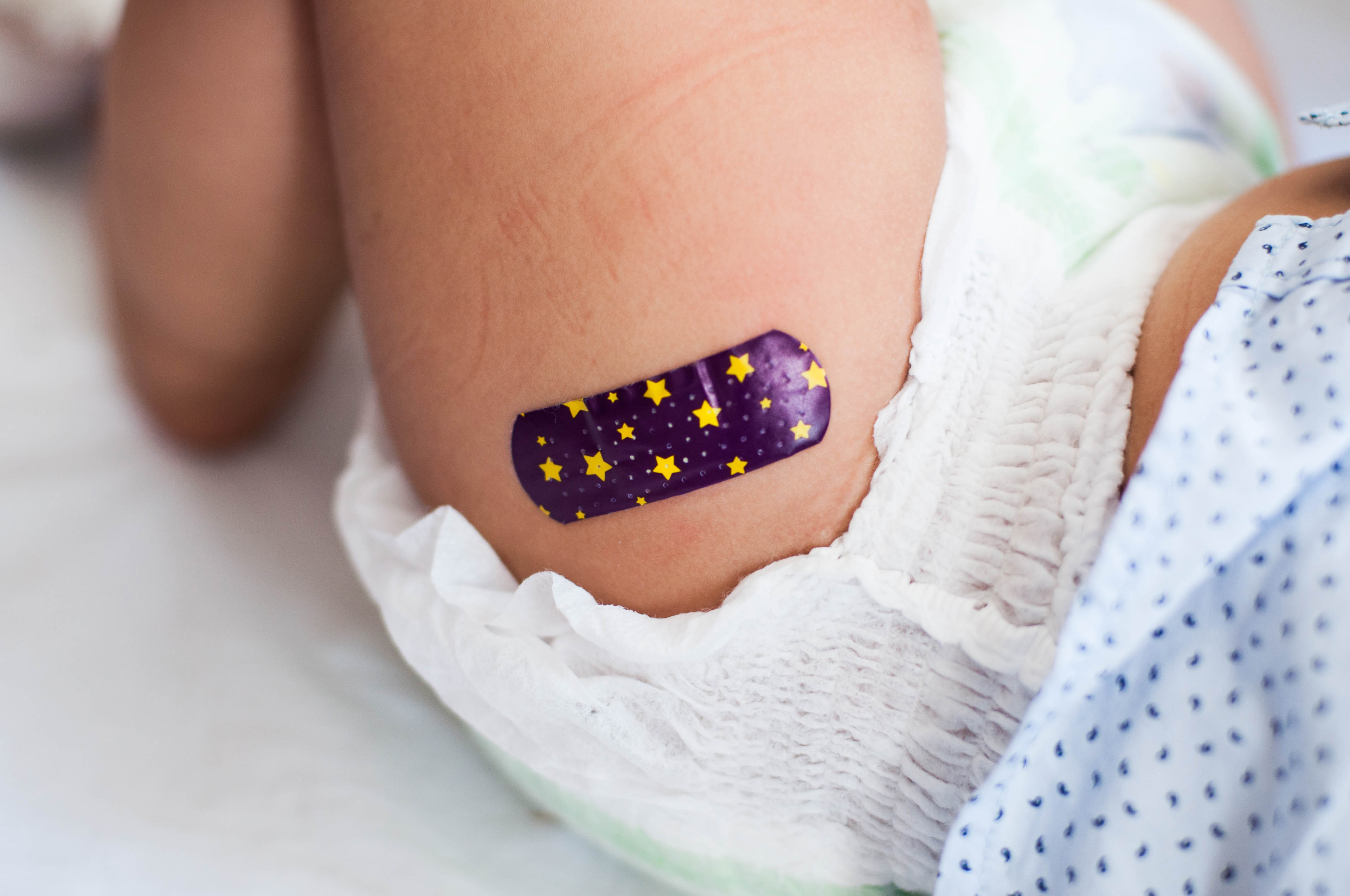 A photo of a newborn with a bandage after vaccination.