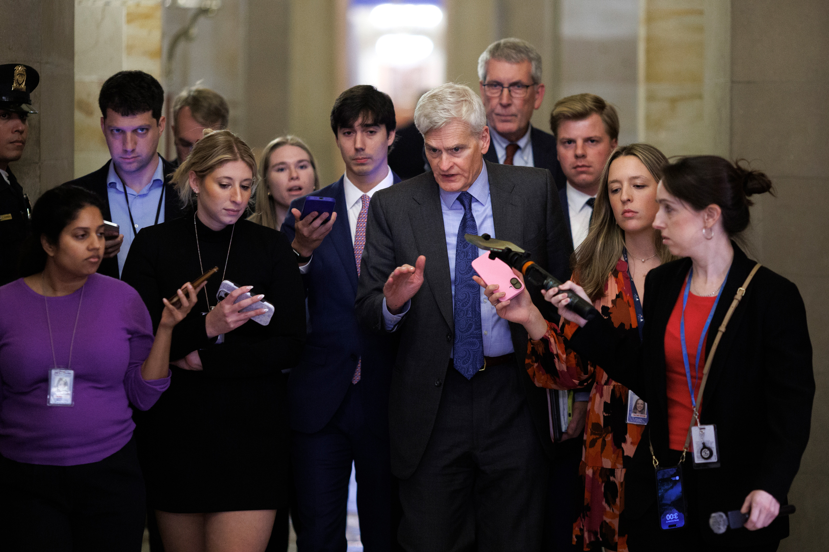 A photo of Sen. Cassidy walking as reporters flank him on both sides.