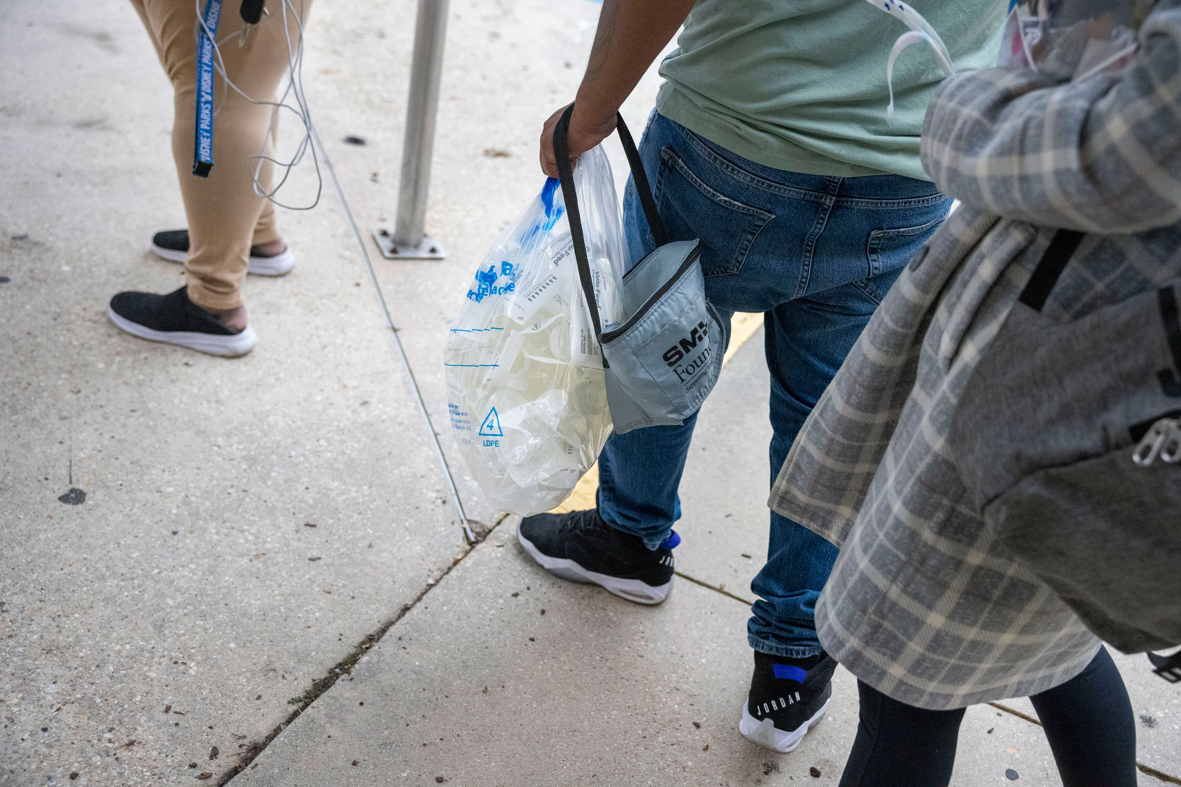 A shot of three people from the waist-down, standing on a sidewalk.