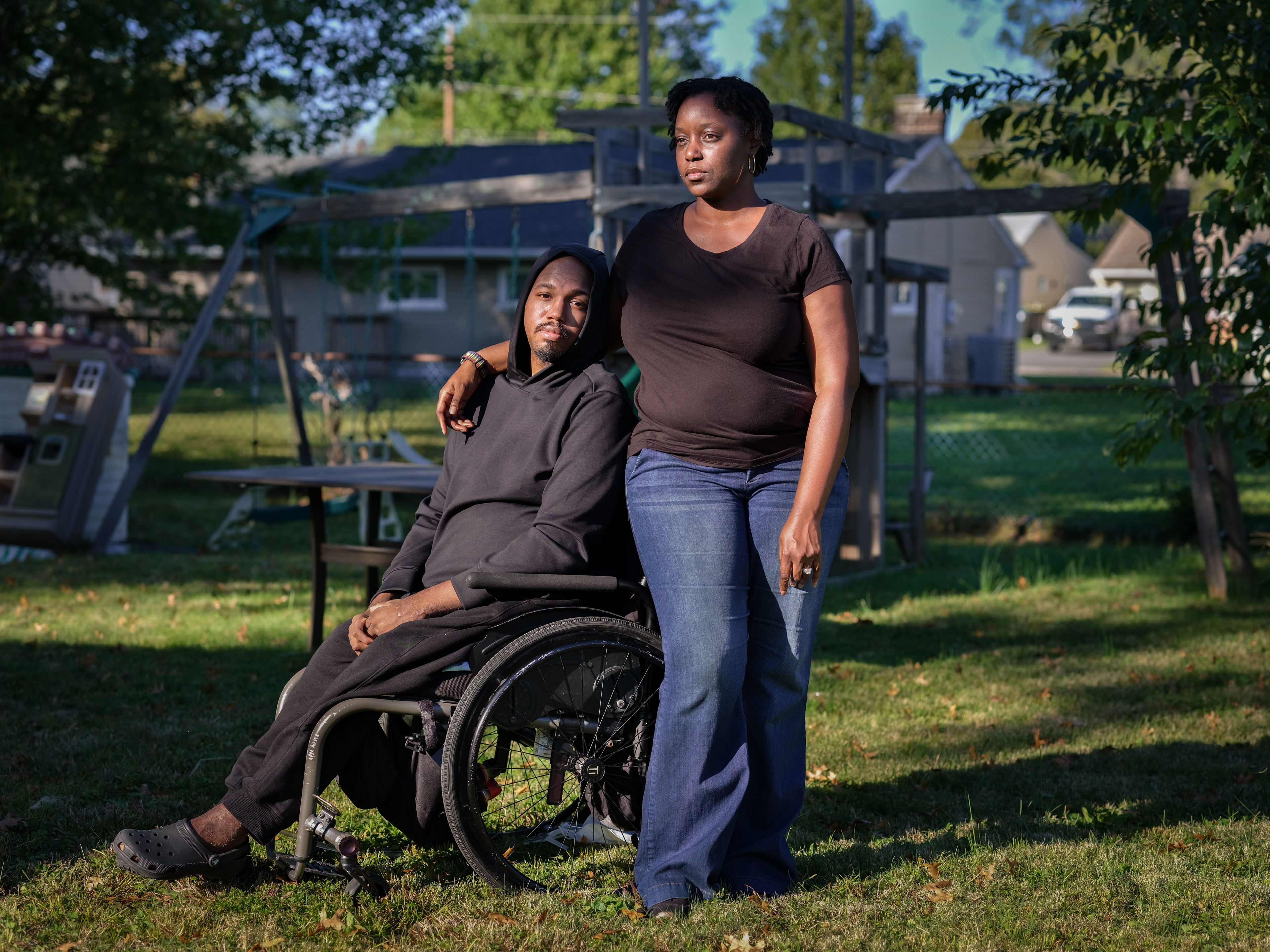 A photo of a Leon Harris seated in a wheelchair posing next to his wife outside.