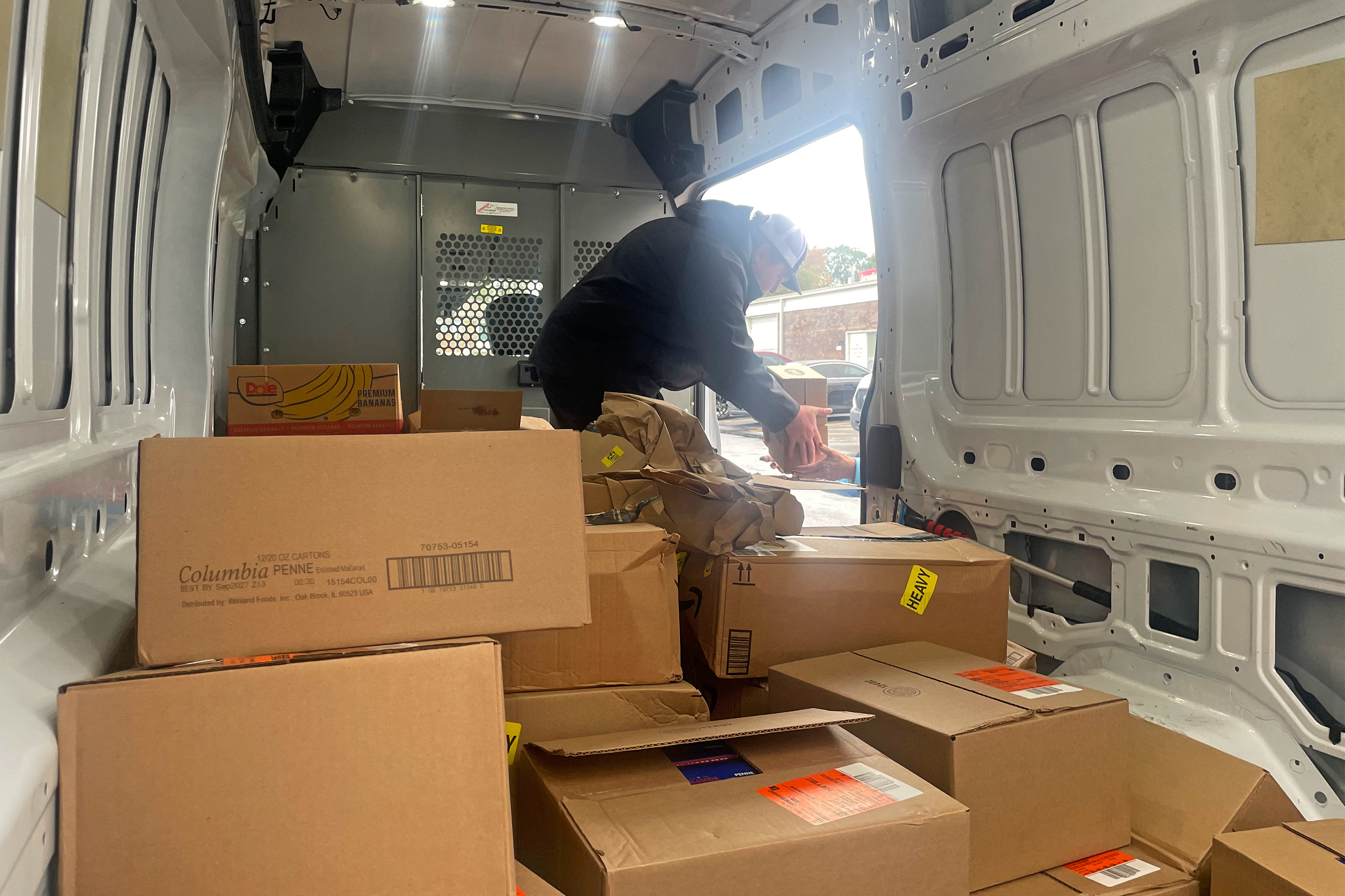 A man unloads boxes from the inside of a white delivery truck