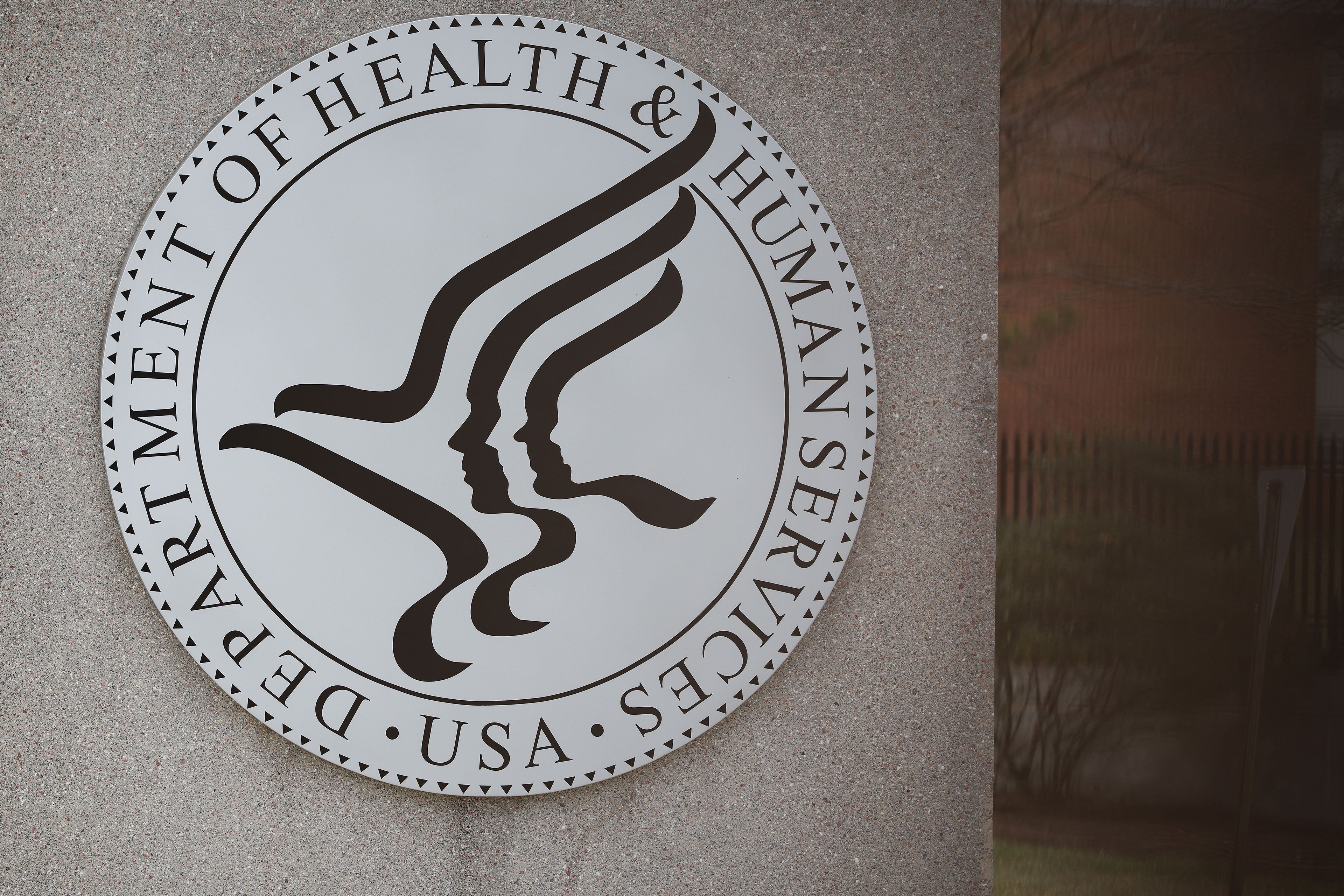 The emblem of the Department of Health & Human Services is shown on the side of a building