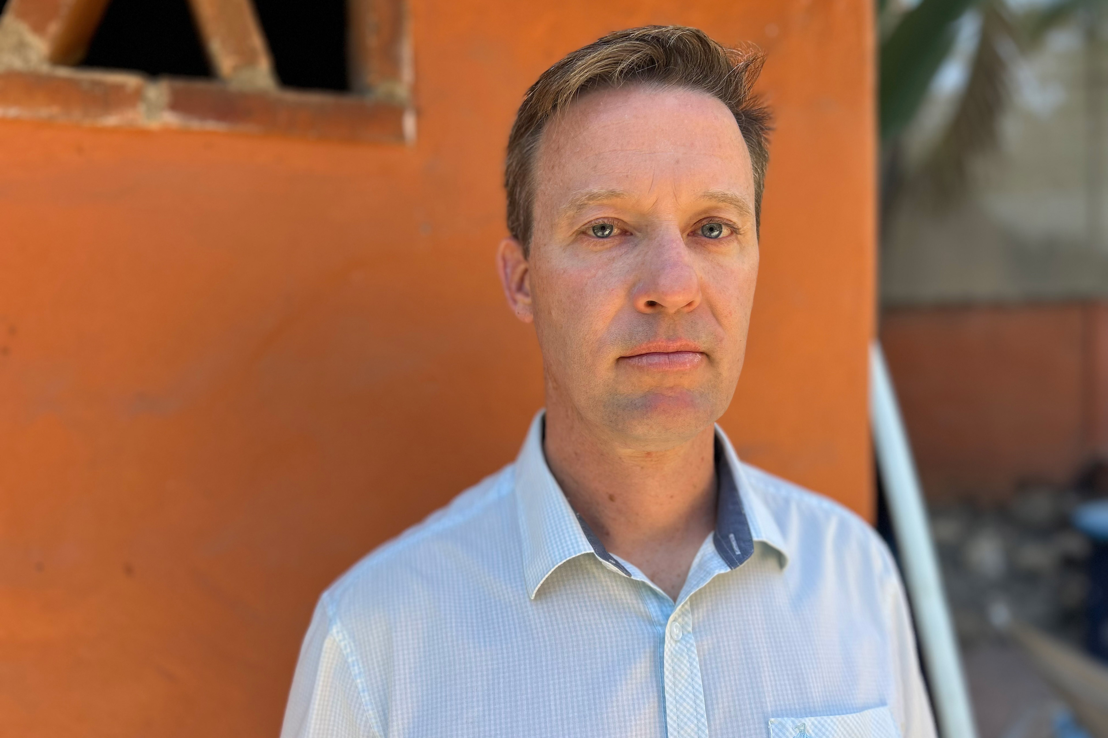 Daniel Dulebohn stands outside in front of a building painted orange.