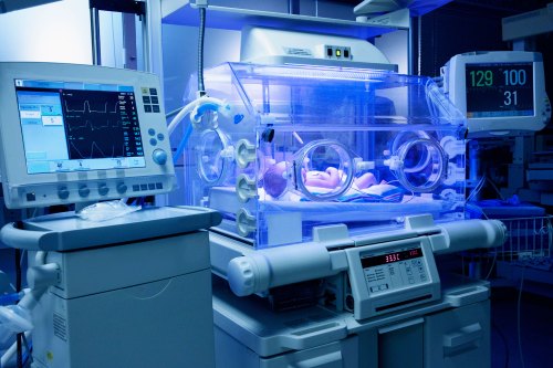 A baby lies in an incubator in a neonatal intensive care unit.