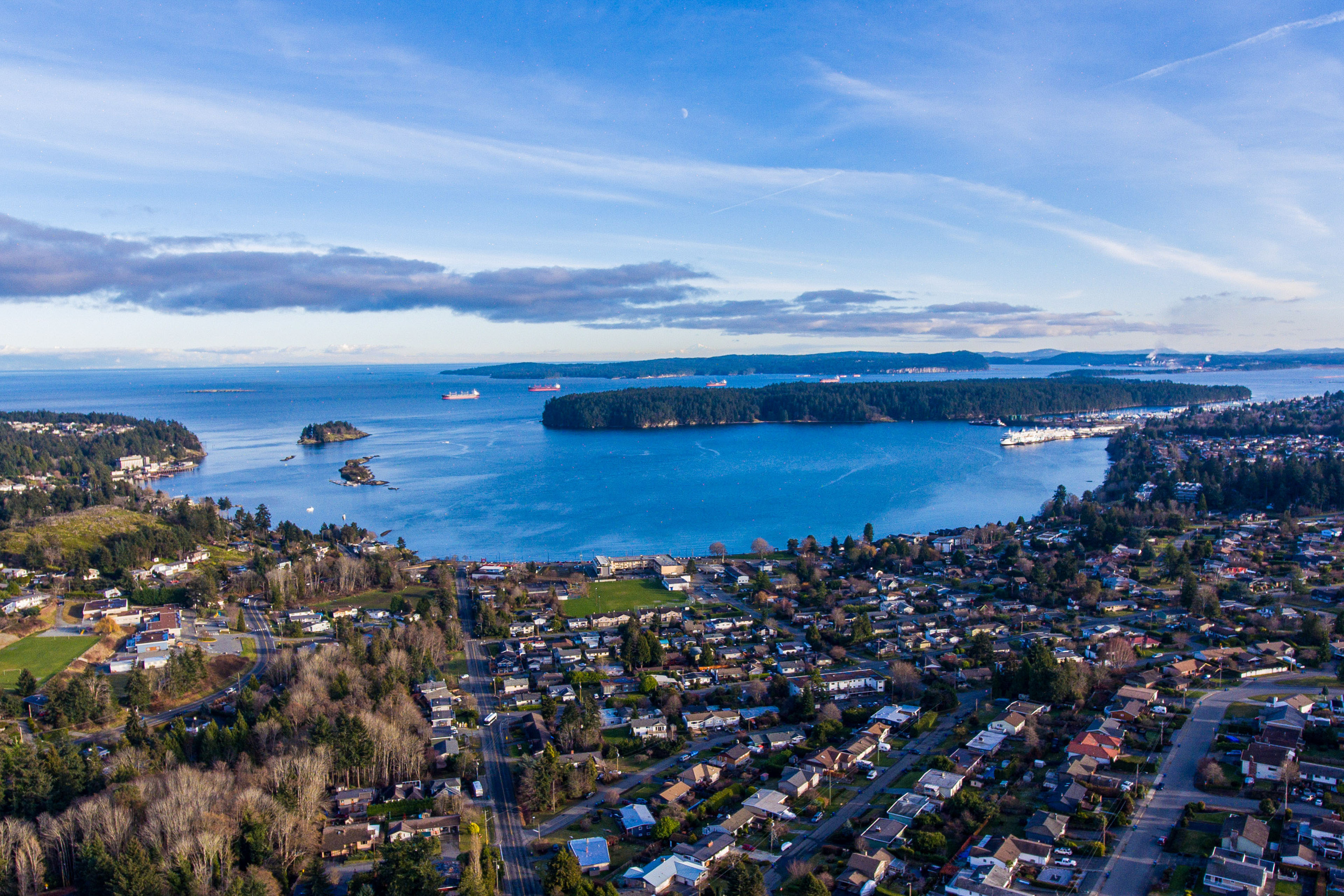 An aerial shot of a city next to a bay with an island in the middle of the bay