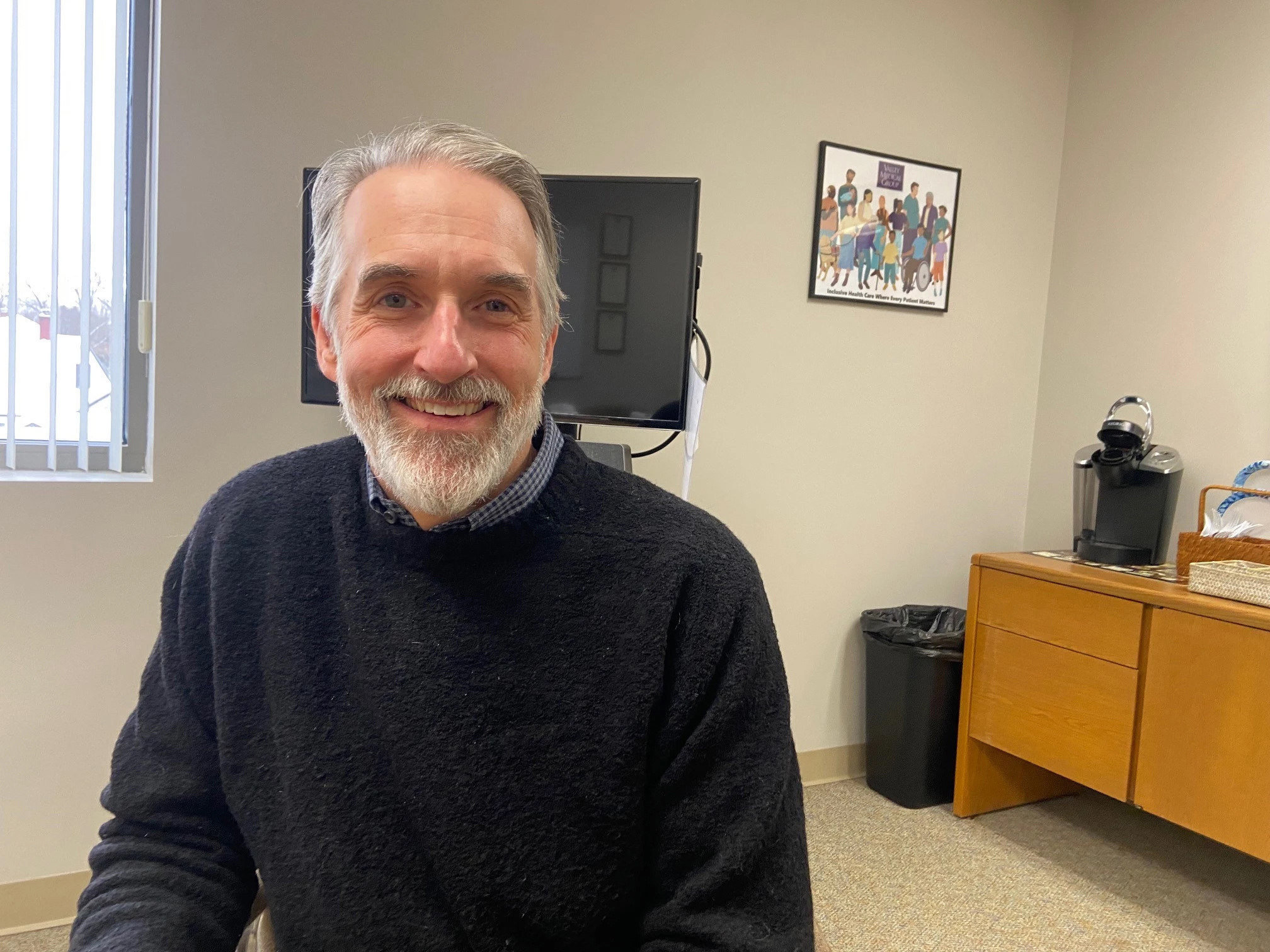Photo of an older man with a grey beard and navy sweater.