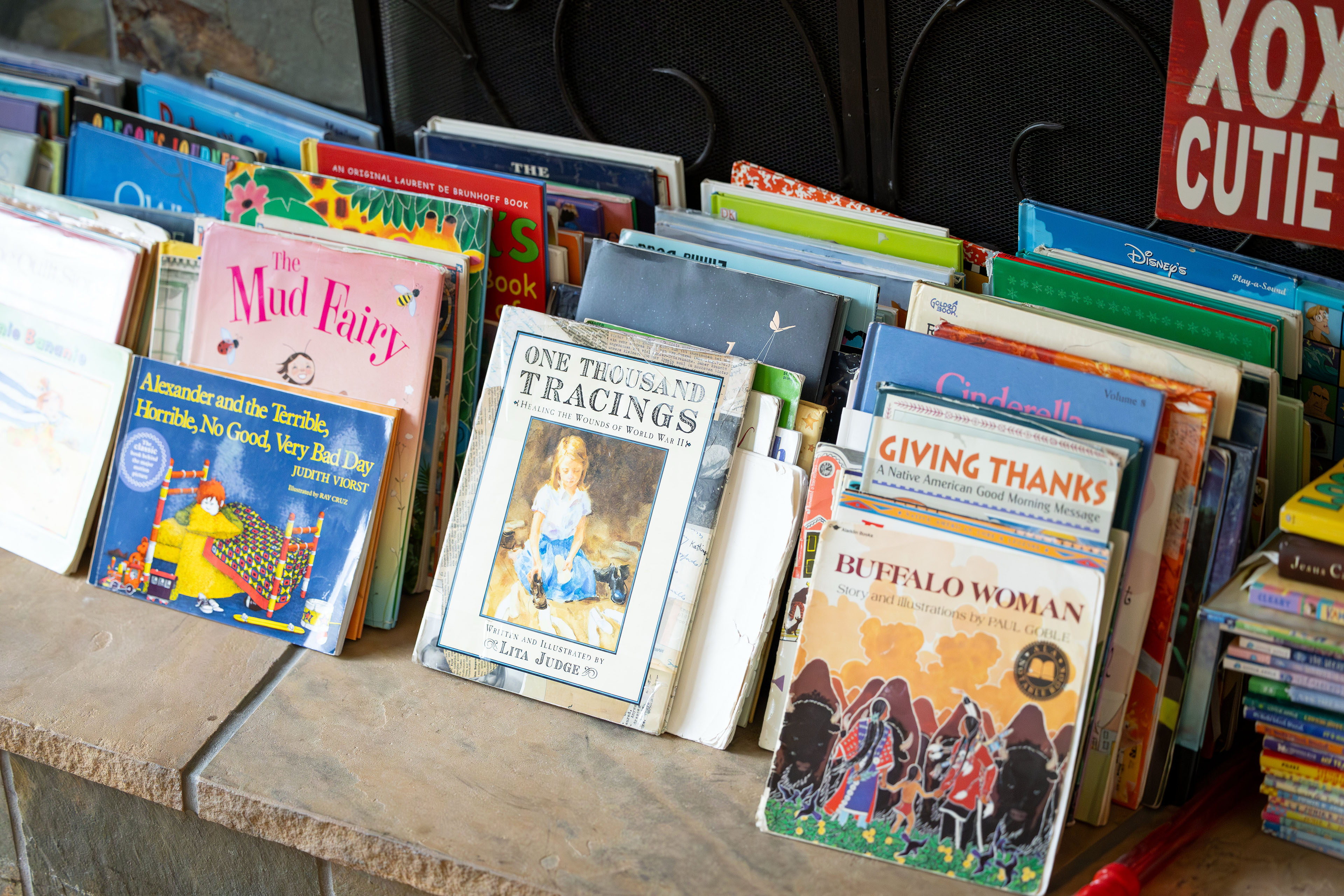 Books are displayed on the hearth of a fireplace.