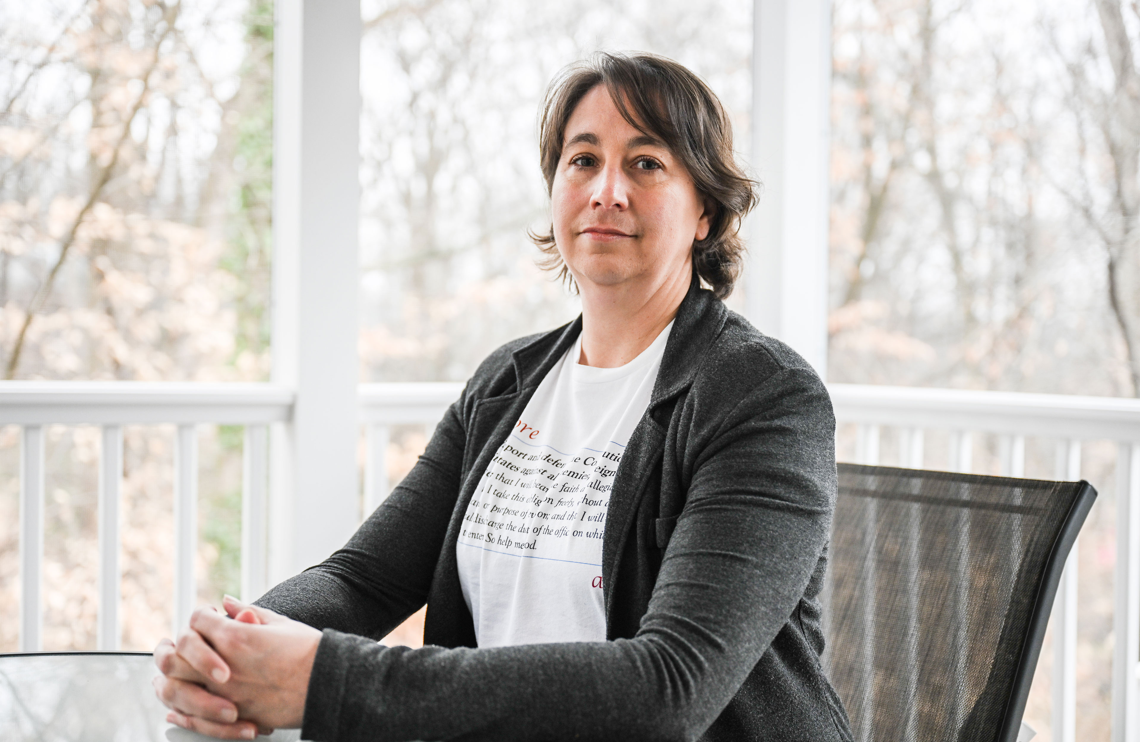 Alexa Romberg sits at a table on a screened-in deck outside.