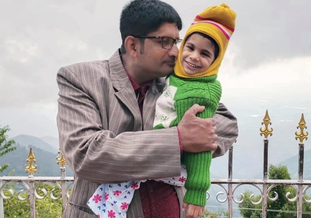 A father holds his young daughter outside.