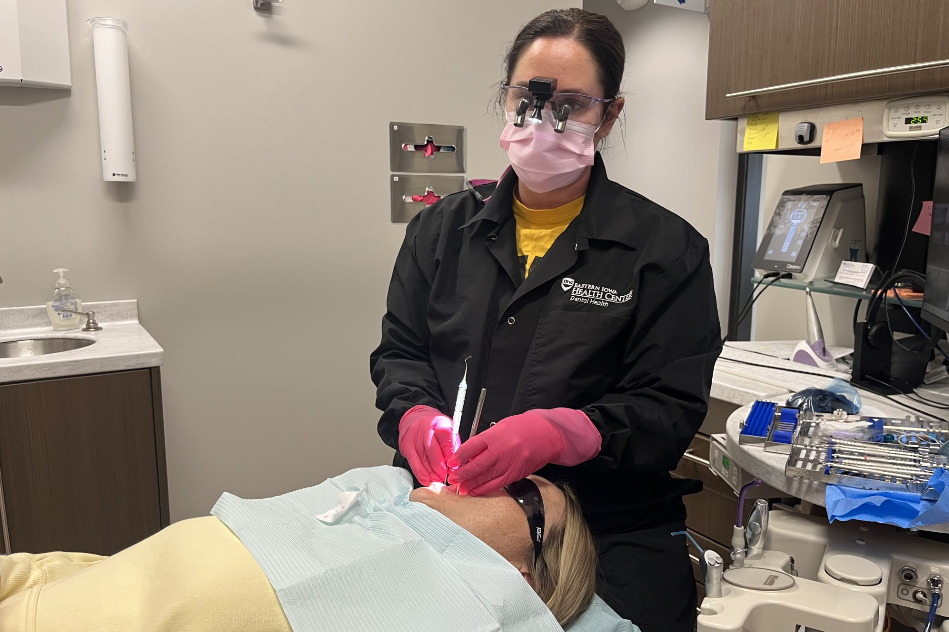 A dental hygienist works on a patient in a dental chair.