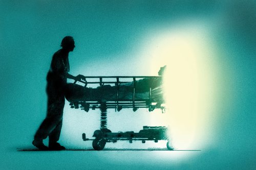 A photo illustration of a medical worker pushing a patient in a gurney. The end of the gurney is dissolving into the void.