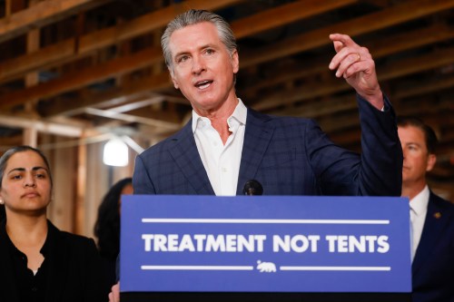 Governor Gavin Newsom speaks at a podium that says, "treatment not tents."