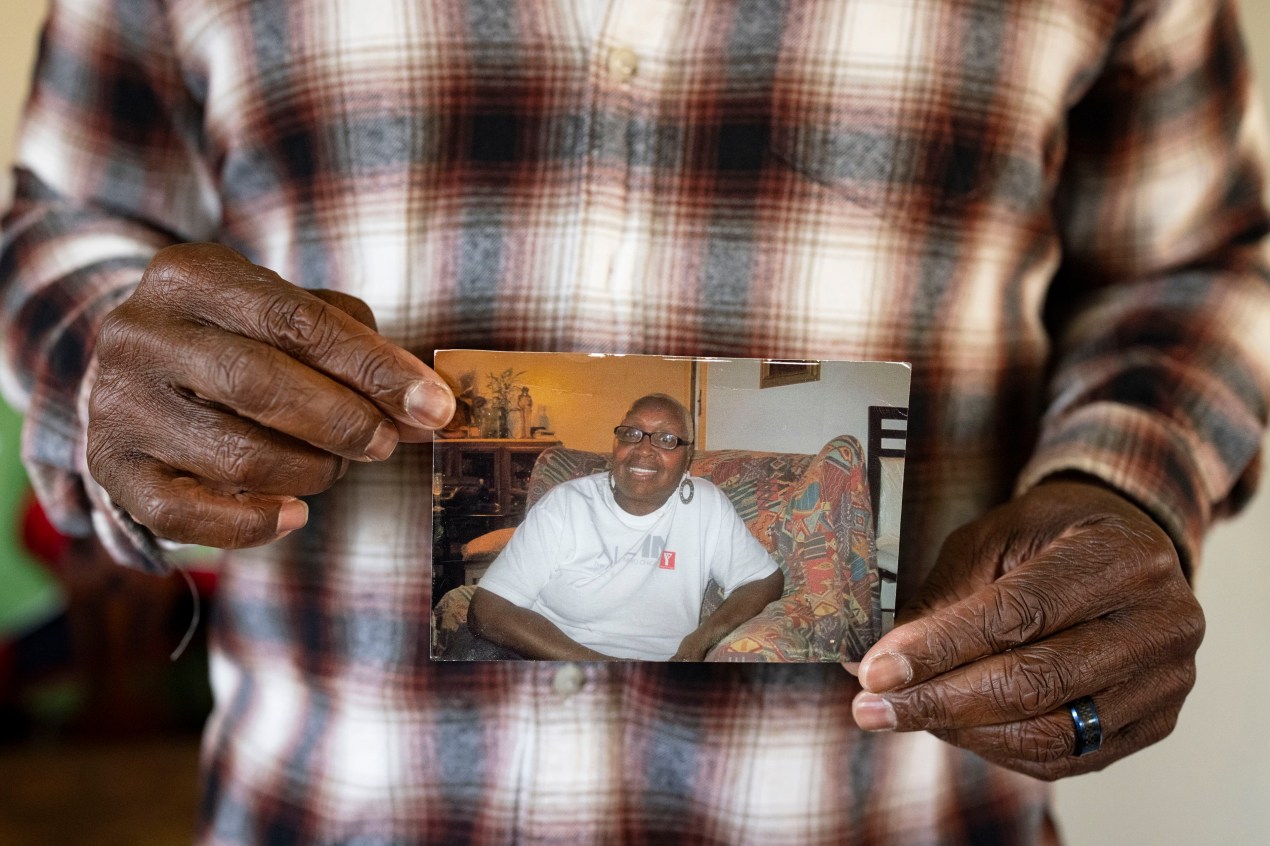 A man holds a paper photograph of a woman in his hands for a photo