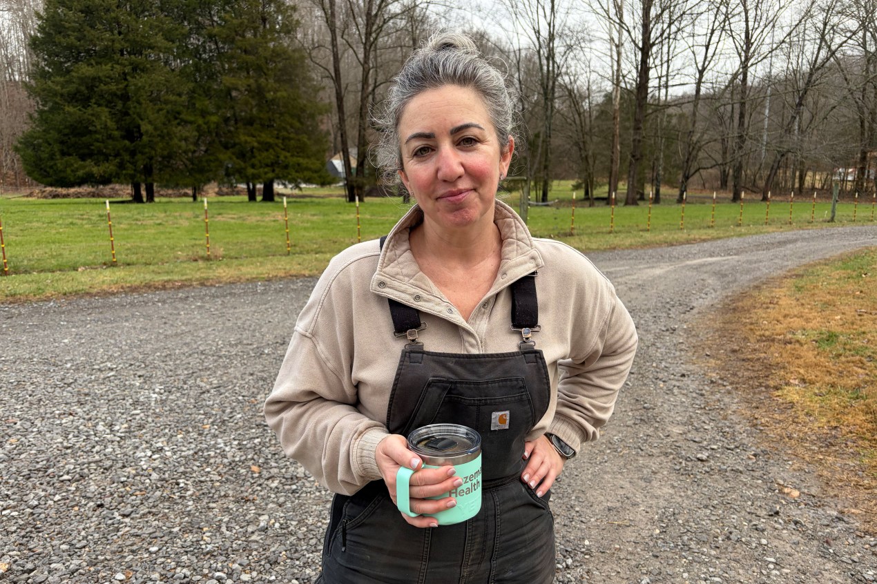 RaDonda Vaught stands at her farm. She smiles slightly, holding a cup of coffee.