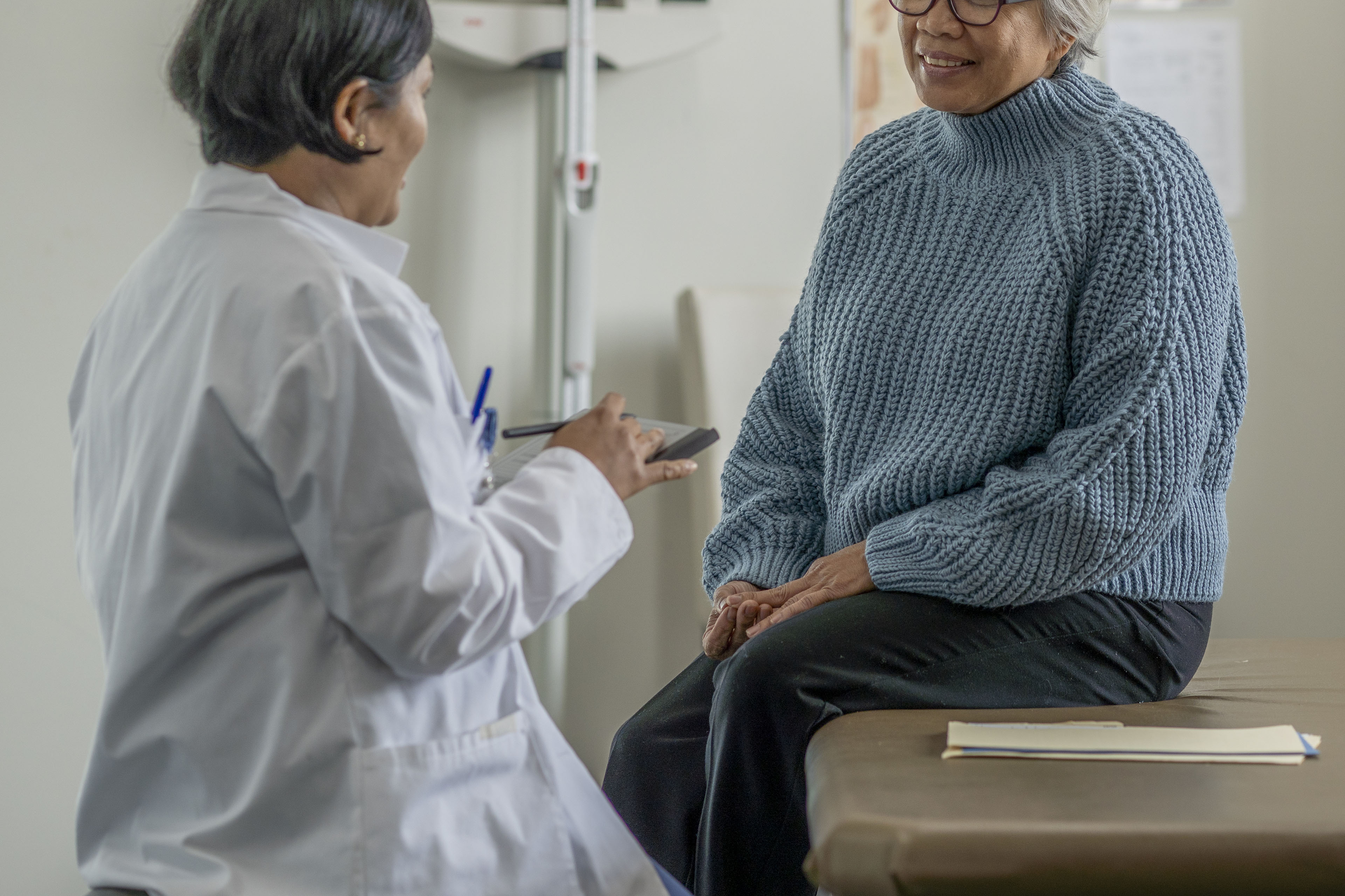 A woman smiles in conversation with her doctor during an appointment.