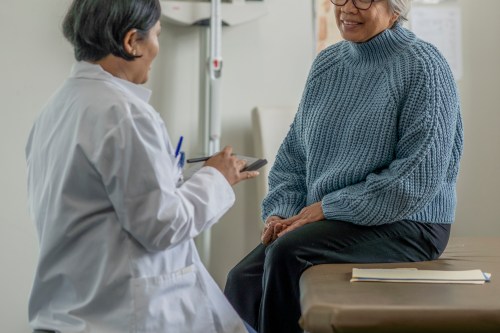 A woman smiles in conversation with her doctor during an appointment.