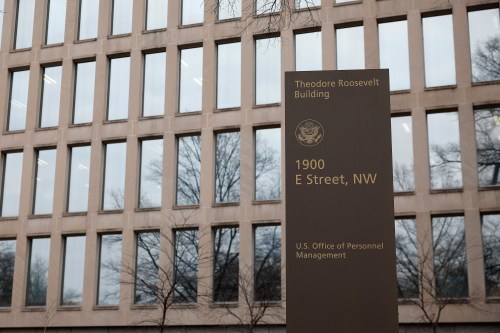 An exterior photograph of a beige building with rows of rectangular windows. A sign in front of the building designates that it is the Theodore Roosevelt Federal Building.
