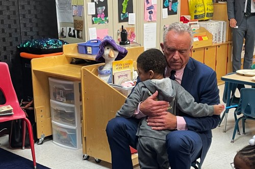Robert F. Kennedy Jr. hugs a child at a childcare center.