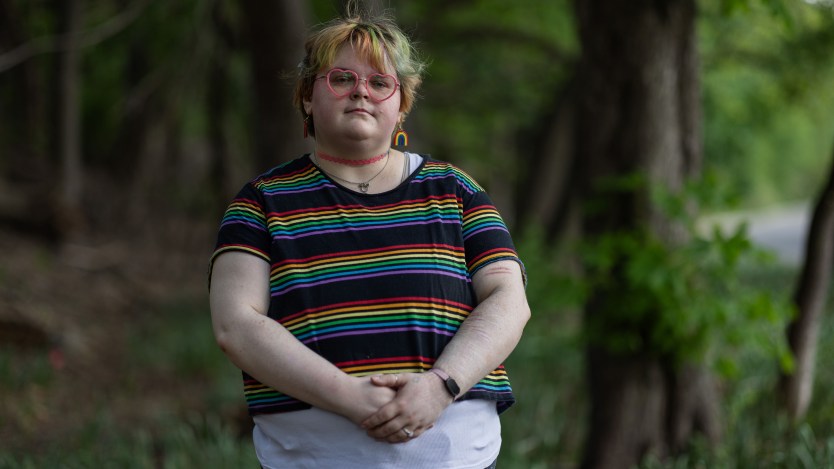 A portrait of a young person wearing a rainbow T-shirt and heart-shaped glasses.