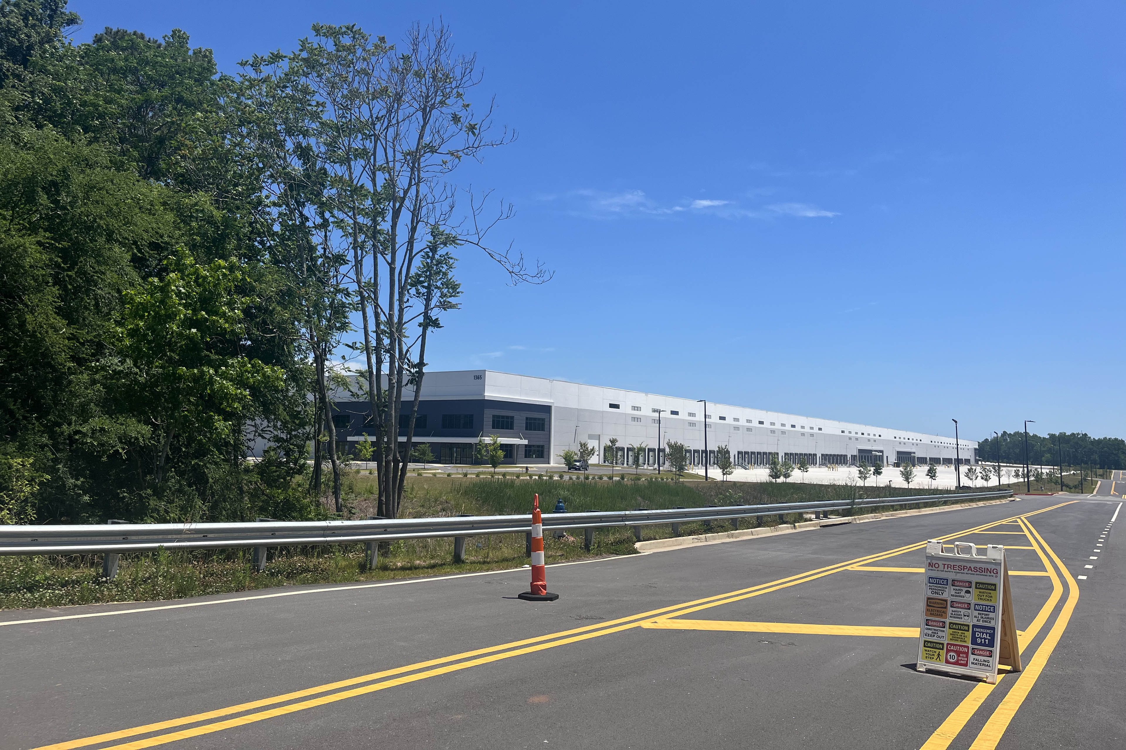 A massive warehouse is visible on the far side of a highway.