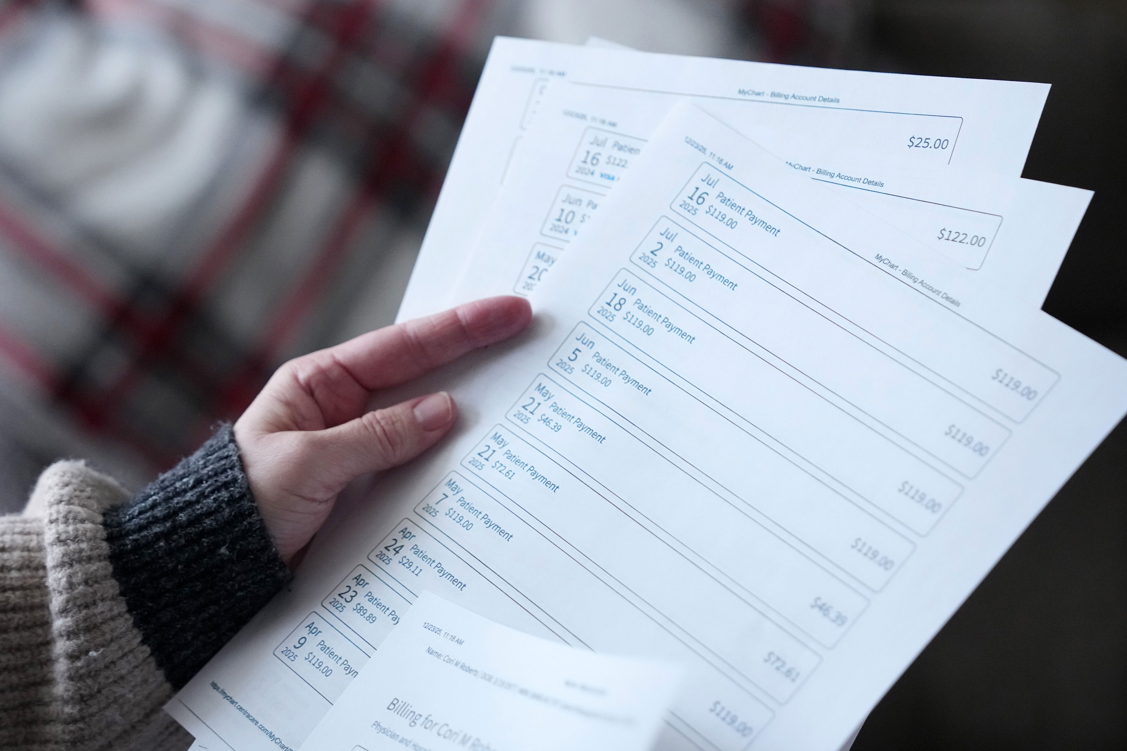 A hand holds at least four sheets of paper printed with the date and amounts of payments. There are 10 payments listed on the clearest page.
