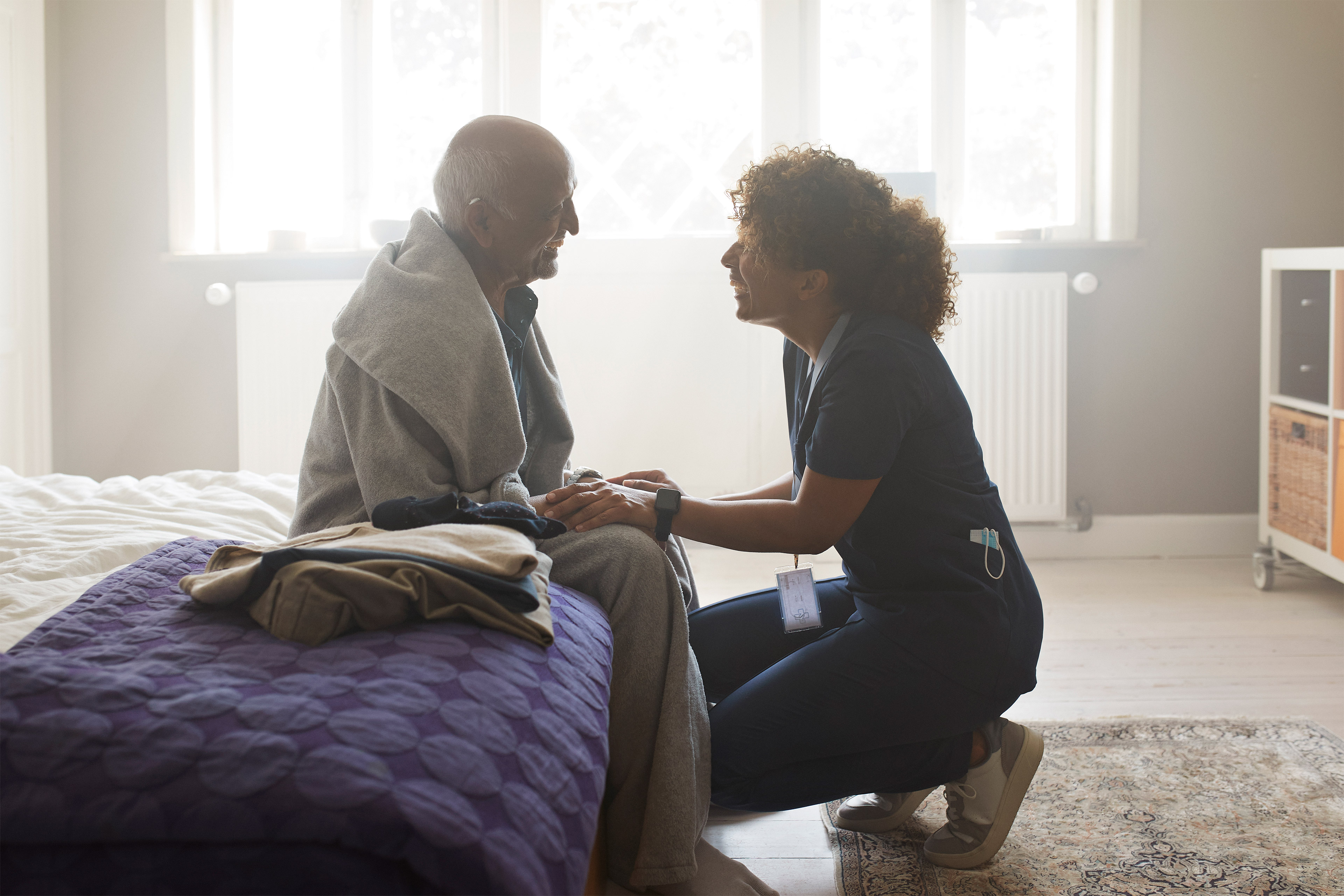 A nurse offers home care to an elderly male patient.