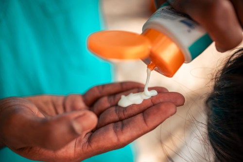 A man squeezes sunscreen into his hand from a tube.