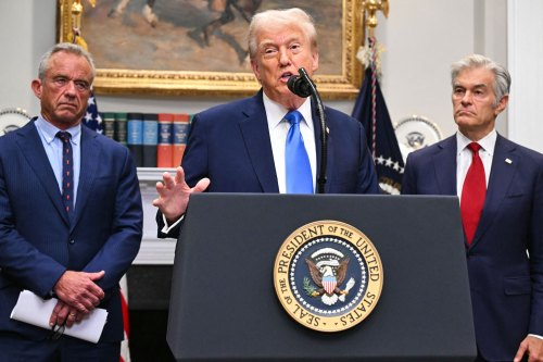 A photo of President Donald Trump at a podium. Robert F. Kennedy Jr. stands to his right. Mehmet Oz stands to his left.