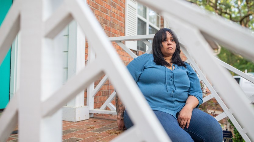 A woman sits on steps on her front porch.