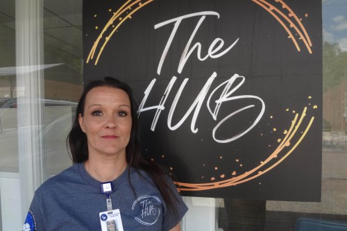A woman stands in front of a sign that says, "the hub."