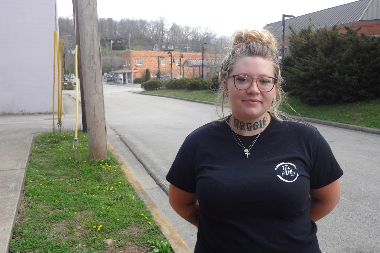 A young woman in a T-shirt with a "The Hub" logo stands for a portrait.