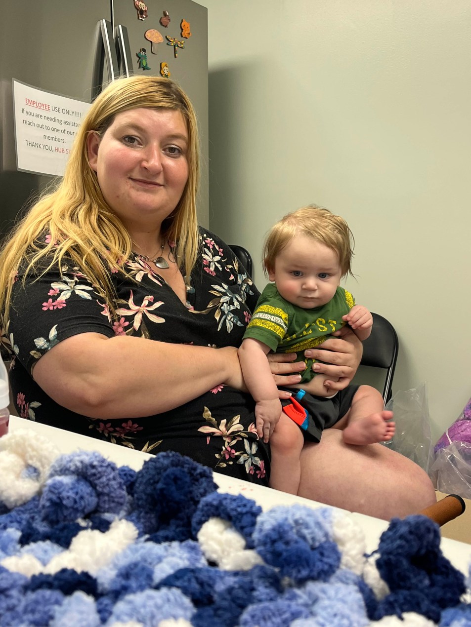 A woman sits with her toddler son on her lap for a photo.